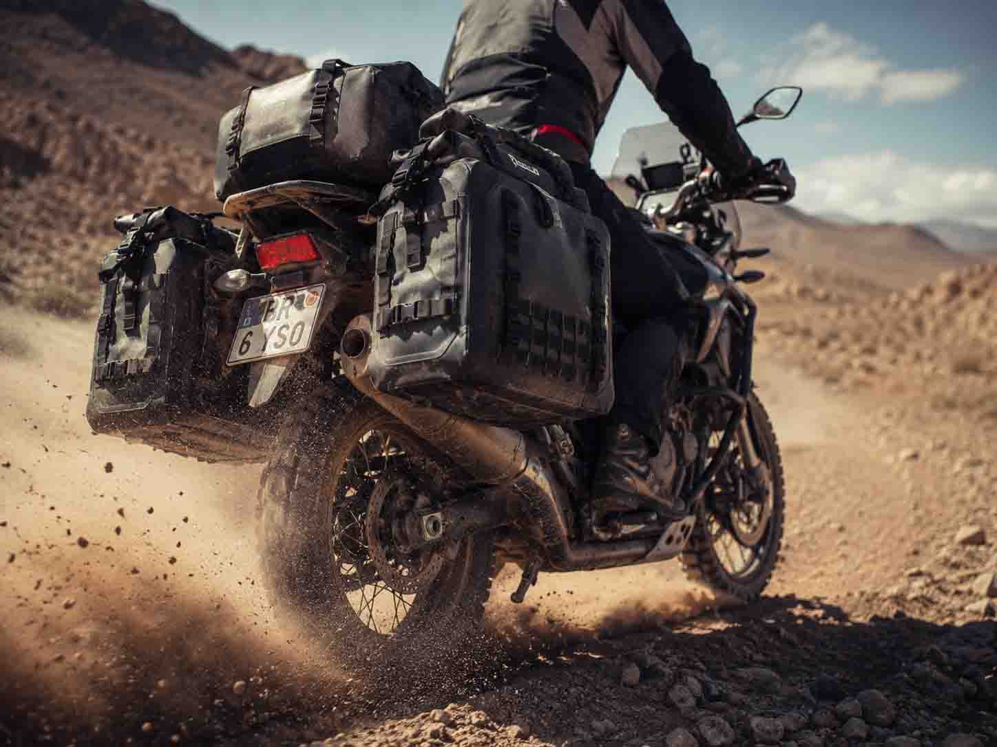 OEM heavy-duty waterproof motorcycle panniers surviving extreme vibration on a desert overlanding adventure.