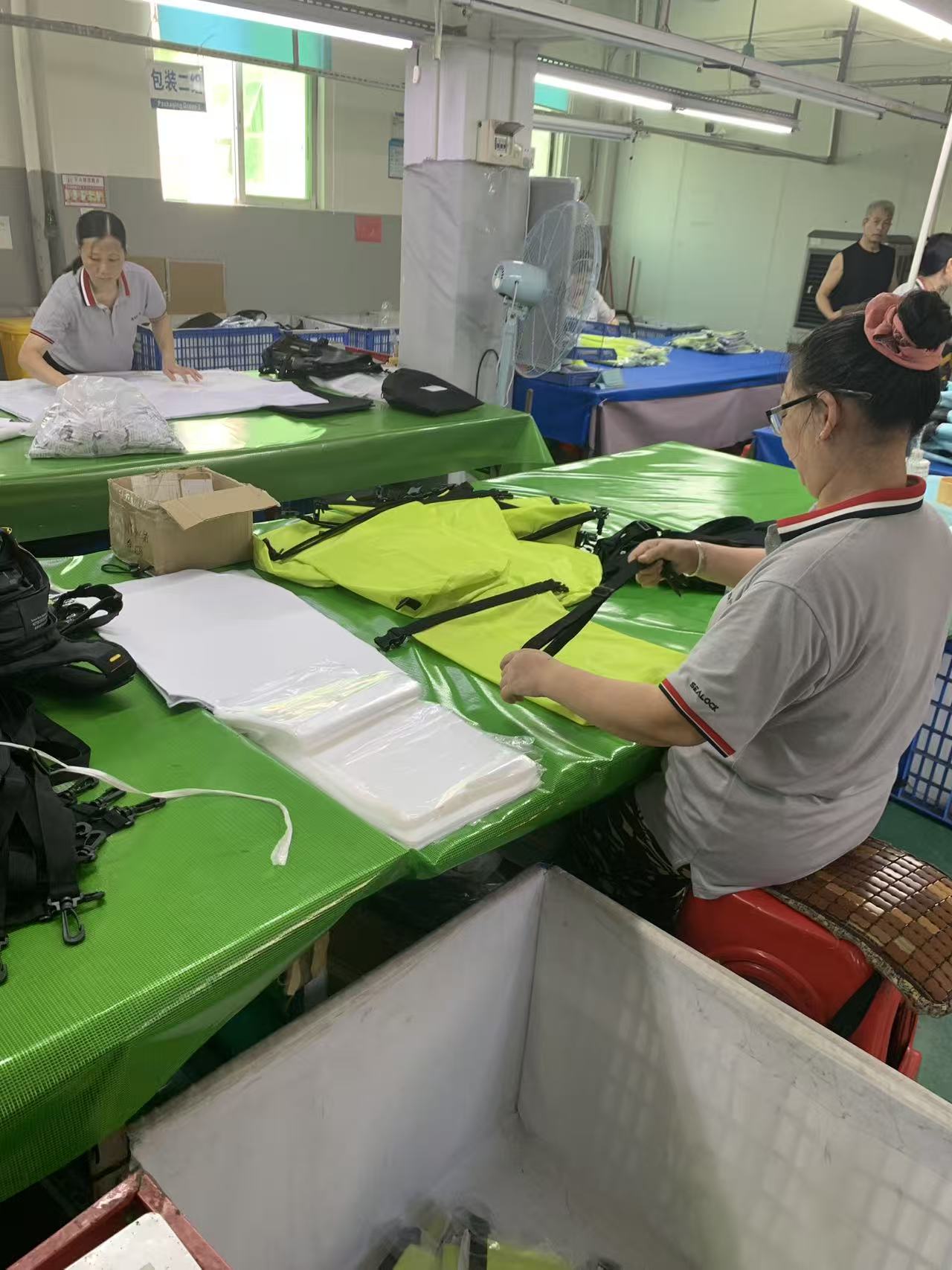 Operator attaching webbing straps and buckles to a high-visibility dry bag